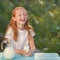 Milk is fresh from the cow - a beautiful girl with dairy products. Girl holds glass with fresh milk. Happy redhead child in summer
