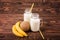 Milk and fruits on a brown background. Delicious bananas and a nutritious coconut. Two mason jars with tasty milk.