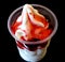 Milk icecream with strawberry sauce in takeaway cup on black background