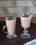 Milk iron with green puff, sprinkled with chocolate in two glass goblets on a table covered