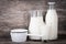 Milk in jug, glass, saucepan and bottle on wooden background.