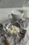 Milk kefir grains in a glass bowl with a cup and a bottle of kefir on white table.