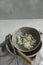 Milk kefir grains in a gray plate with a strainer and a spoon on white background.