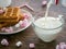 Milk is poured into a cup from a bottle. Cookies and sweets are on the saucer.