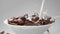 Milk is poured to the bowl with chocolate corn flakes in slow motion, drops of milk falling in 240fps to the cocoa