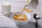 Milk pouring into a bowl of delicious corn flake cereals and cap with espresso coffee. Morning breakfast.