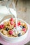 Milk pouring into plate with granola and fresh berries