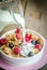 Milk pouring into plate with granola and fresh berries