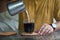 Milk pouring from a small pitcher into glass with black coffee