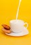 Milk pours into a cup, on a saucer a cookies