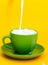 Milk pours in a cup on a yellow background. Healthy eating concept