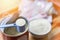 Milk powder in spoon with can and baby bottle milk in bowl on wooden table