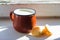 Milk in small mug and kurt standing on windowsill in sunny day