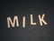 Milk written with colorful wooden letters on a black background