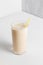 Milkshake with banana in high transparent glass on a white background. A healthy drink for a diet