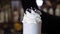 Milkshake with whipped cream in a tall glass. Decoration with chocolate topping and cocktail tubes.