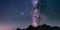 The Milky Way core and glowing stars in the night sky oover the Alps. Panoramic view high mountain range silhouette. Jupiter