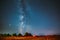 Milky Way Galaxy In Night Starry Sky Above Haystack In Summer Agricultural Field. Night Stars Above Rural Landscape With