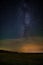 The milky way over the field and the city light over the horizon.