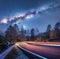 Milky Way over mountain road. Blurred car headlights