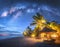 Milky Way over the sandy beach with palm trees and sunbeds