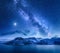 Milky Way over snow covered mountains and sea at night in winter