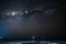 Milky Way starry sky glowing stars in the night on tropical island blurred boats in the sea Indonesia Kei Islands Moluccas Maluku