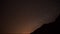 Milky Way Timelapse. Stars at Night Orange Sky Moving Above Mountain Hill