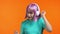 Millenial woman with dyed violet hairstyle dancing with headphones on orange studio background. Cute girls portrait