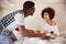 Millennial African American couple celebrating, man serving his partner breakfast in bed, close up