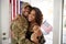 Millennial African American  soldier and wife embracing at home and smiling to camera,waving flag, close up