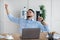 Millennial Arab businessman stretching his sore muscles at workplace, sitting at desk with laptop in modern office