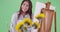 A millennial asian woman paints near sunflowers on green screen