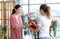 Millennial Asian young cheerful female customer standing smiling receiving holding pink rose sample from unrecognizable unknown