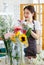 Millennial Asian young female flower shopkeeper decorator florist employee worker in apron smiling arranging decorating taking