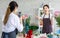 Millennial Asian young female flower shopkeeper decorator florist employee worker in apron standing smiling in store flowers