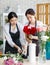 Millennial Asian young professional female florist shopkeeper employee worker wearing apron holding red roses bunch bouquet while