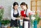 Millennial Asian young professional female florist shopkeeper employee worker wearing apron holding red roses bunch bouquet while