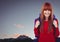 Millennial backpacker smiling against evening sky and mountain tops