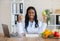 Millennial black dietitian holding apple and showing thumb up gesture at desk in medical office. Healthy eating concept