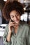 Millennial black female creative in an office using smartphone, looking down, close up, vertical