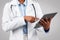 Millennial black woman doctor therapist in white coat, chatting at tablet, typing on gadget