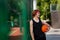 Millennial Caucasian basketball player with ball standing near fence at stadium, empty space