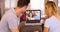 Millennial couple video chatting with their parents on laptop