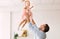 Millennial dad throwing little girl up in the air