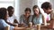 Millennial different ethnicity friends sitting at table assembling jigsaw puzzle