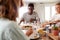 Millennial friends eating lunch together at a sitting at dinner table, close up