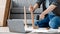 Millennial guy fixing furniture, repairing wooden table uses electric drill, sits on floor at home