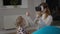 Millennial mother in VR headset playing online as baby daughter looking at parent with surprised facial expression