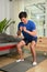 Millennial muscular asian male doing squatting exercises in living room. Healthy lifstyle, sport and motivation concept